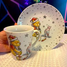 a winnie the pooh coffee cup and saucer set on a table in front of a christmas tree