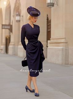 a woman in a dress and hat is walking down the street