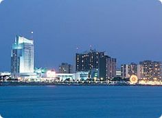 the city skyline is lit up at night from across the water with buildings in the background