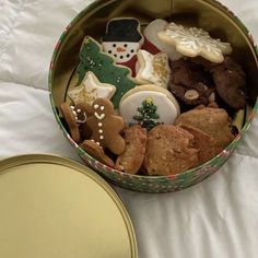 a tin filled with lots of cookies on top of a bed