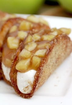 two pieces of food on a white plate with apples in the backgroung