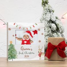 a baby's first christmas photo frame next to a present box with a red bow