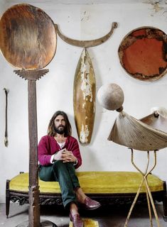 a man sitting on top of a yellow bench in front of some art pieces and lamps