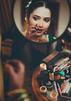 a woman is looking into a mirror with makeup on her face and make - up in front of her