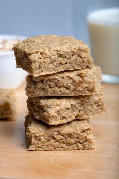 some oatmeal bars stacked on top of each other next to a glass of milk