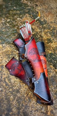 two red and black leather bags with arrows in them sitting on the ground next to some rocks