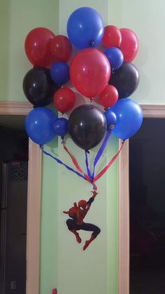 a bunch of balloons that are in the shape of a spiderman hanging from a wall