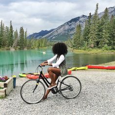 a woman riding a bike next to a lake