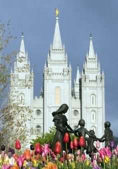 there is a statue in front of a castle with tulips and other flowers