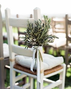 a white chair with a plant on top of it next to other chairs in the grass