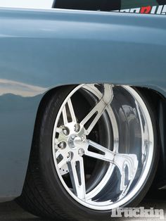 the front wheel of a blue car with chrome spokes