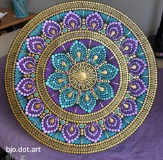 an artistically painted plate sitting on top of a purple tablecloth with gold and blue designs