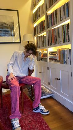 a man sitting on a chair in front of a bookshelf