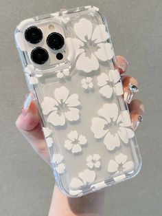 a woman holding an iphone case with white flowers on the front and back, in her hand