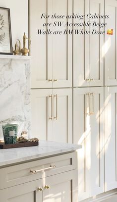 a kitchen with white cabinets and marble counter tops