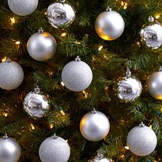 many silver and white ornaments hanging from a christmas tree