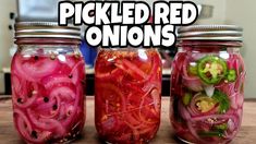 three jars filled with pickled red onions sitting on top of a wooden table next to each other