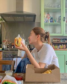 a woman sitting at a kitchen counter eating a sandwich