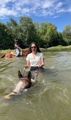 a woman riding on the back of a horse in water