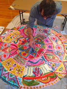 a man is working on a colorfully designed tablecloth at a crafting workshop