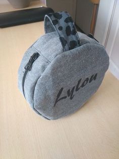 a gray and black bag sitting on top of a wooden table