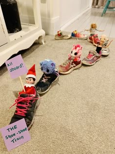 elf shoes lined up on the floor with signs attached to them