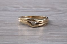 two gold wedding bands with a diamond in the middle on a wooden surface, close up