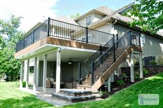 a house with stairs leading up to the front door and second story deck area on top of it