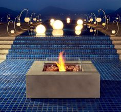 a fire pit sitting on top of a blue tiled floor next to steps and lights