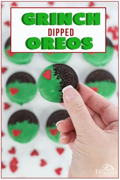 a hand holding an oreo cookie in front of green and red cupcakes