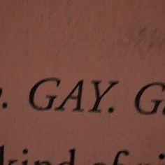 a close up of the word g gay on a wall with black writing in it