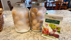 two jars filled with food sitting on top of a counter next to a bag of seeds