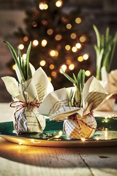 two paper flowers sitting on top of a green plate next to a lit christmas tree