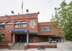 an old brick building with two bicycles parked in front of the entrance and stairs leading up to it