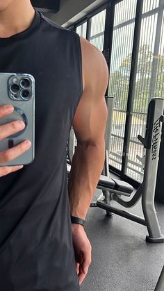 a man taking a selfie in the gym with his cell phone and water bottle