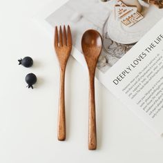 two wooden spoons and fork sitting on top of a magazine