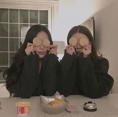 two women are holding up their faces with cookies in front of them