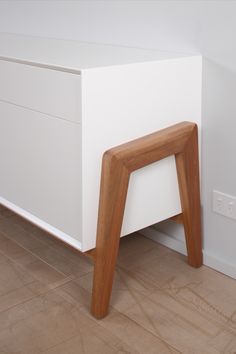 a white dresser with wooden legs in a room