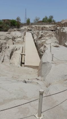 a stone walkway in the middle of a desert with rocks and chains on each side