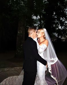 a bride and groom kissing in front of trees