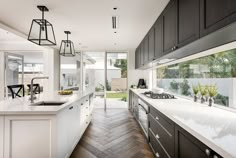 a large kitchen with white counter tops and wooden flooring next to a dining room table