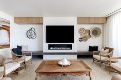 a living room with white furniture and a flat screen tv mounted on the wall above a fireplace