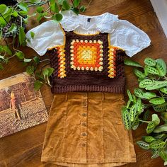 there is a shirt and skirt on the table next to some green plants, with an old photo in the background