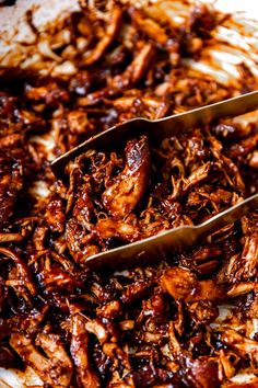 two spoons are being used to scoop barbecue pulled pork