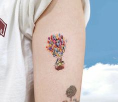 a person with a tattoo on their arm holding a candy bar hot air balloon in the sky