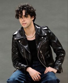 a man in a black leather jacket is sitting down