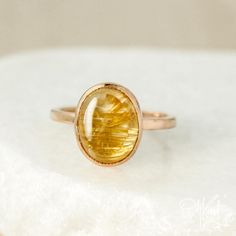 Bright or demure, this small collection of Golden Yellow Rutile Quartz Rings are perfect for every personal style. Each making a grand statement of their own, these smooth oval golden rutile quartz stones vary in their level of golden tones and design that is created by their natural, needlelike inclusions for a true unique and one-of-a-kind aesthetic. Available in a variety of settings including 925 sterling silver or yellow/rose gold plating, allow these ethereal bezel set rings to add warmth Yellow Saphire Engament Ring, Custom Birthstone Ring, Geode Ring, Rutilated Quartz Ring, Golden Rutilated Quartz, Druzy Jewelry, Bezel Set Ring, Ring Bezel, Rutile Quartz