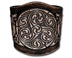 Width: 80mm (3.1inch) Thickness: approx 2,5-3mm (6-7oz) Material: veg-tanned full grain leather (cowhide) Color: black-antique Design: Celtic Spirals with Celtic Dogs (12) / Embossed Fastening: 2 Snap Fasteners, Material: brass (nickel free), Finish: nickel-antique, Design: Triskel Sizes: S to 2XL Embossed and antique dyed strong leather bracelet made of vegetable tanned full grain leather with two snap fasteners. The bracelet has a width of 80mm (3.1inch) and a thickness of approximate 2,5-3mm Viking Wrist Cuff, Leather Wristbands Celtic, Hand-tooled Leather Cuff Bracelet, Gothic Leather Bracelet With Rivets, Engraved Leather Bracelets, Rustic Hand-tooled Leather Cuff Bracelet, Celtic Spiral, Celtic Bracelet, Tree Of Life Bracelet