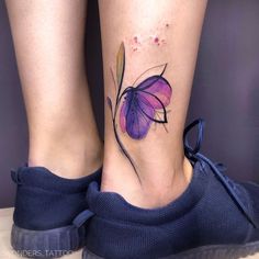 a woman's foot with a purple butterfly tattoo on her left side calfocks