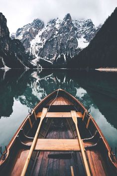 a boat is sitting on the water in front of snow covered mountains and evergreens